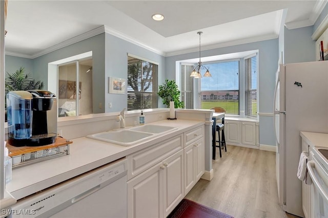 kitchen with sink, ornamental molding, pendant lighting, white appliances, and white cabinets