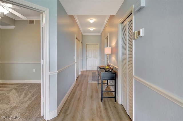 corridor with ornamental molding and light hardwood / wood-style floors