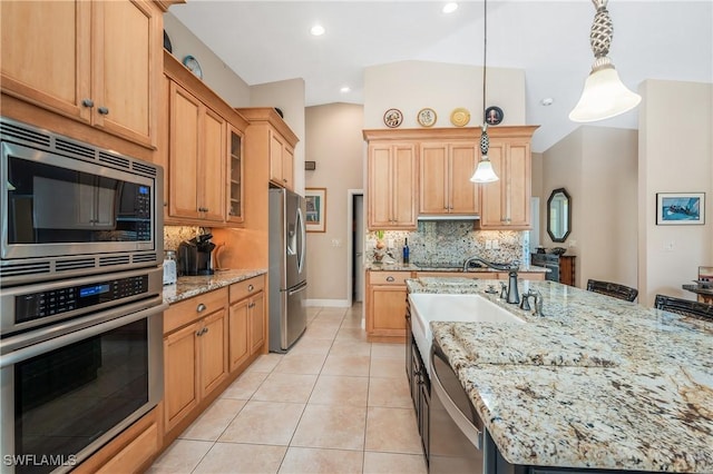 kitchen with appliances with stainless steel finishes, light tile patterned floors, light stone counters, and decorative light fixtures