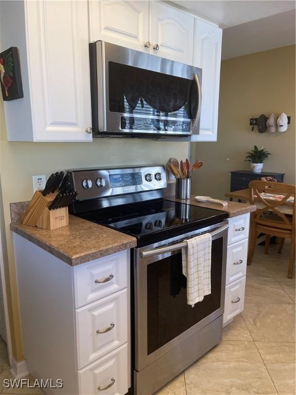 kitchen with white cabinetry, light tile patterned floors, and stainless steel appliances