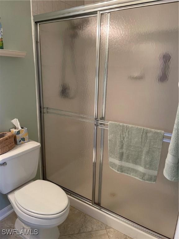 bathroom with an enclosed shower, tile patterned flooring, and toilet