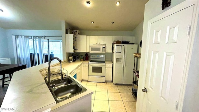 kitchen with light tile patterned flooring, sink, white cabinets, kitchen peninsula, and white appliances