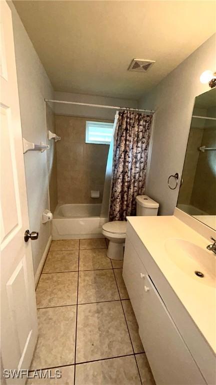 full bathroom featuring tile patterned flooring, vanity, toilet, and shower / bath combo with shower curtain