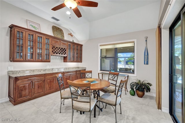 dining room featuring vaulted ceiling, bar area, and ceiling fan