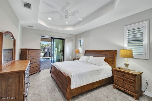 carpeted bedroom featuring a tray ceiling, access to outside, and ceiling fan