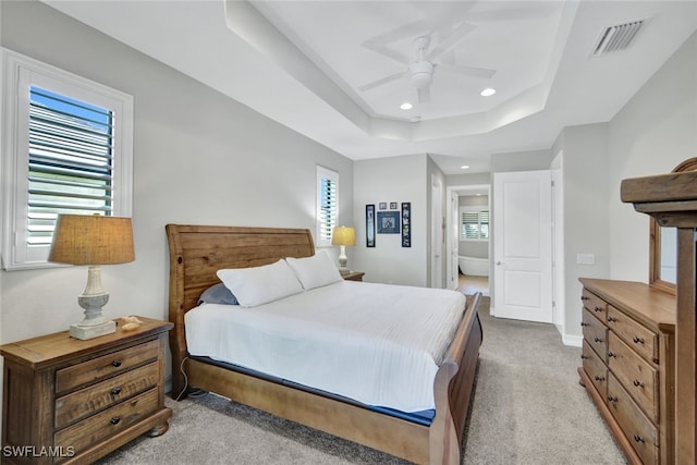 bedroom with a raised ceiling, ceiling fan, light carpet, and multiple windows