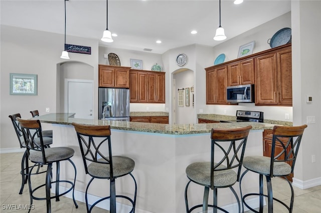 kitchen featuring pendant lighting, light stone counters, stainless steel appliances, and a large island with sink