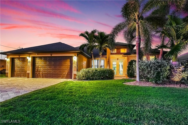 view of front of property featuring french doors, a garage, and a yard