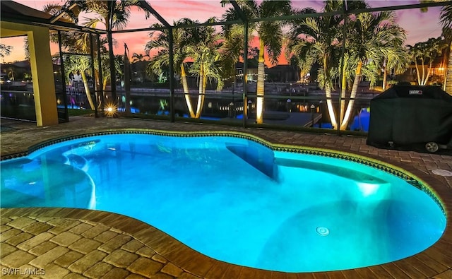 pool at dusk featuring a grill, a lanai, and a patio area