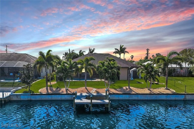 exterior space featuring a water view, a yard, a boat dock, and glass enclosure