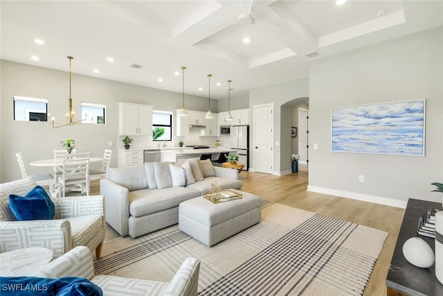 living area featuring baseboards, arched walkways, coffered ceiling, light wood-type flooring, and recessed lighting