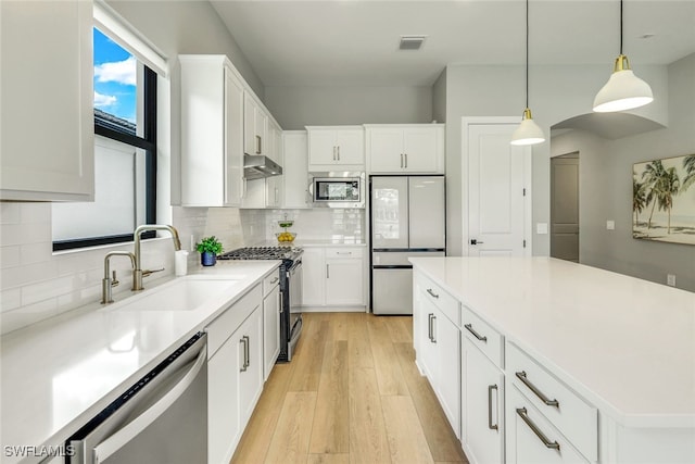 kitchen with visible vents, light wood-style flooring, built in appliances, under cabinet range hood, and a sink