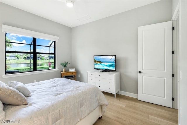 bedroom featuring attic access, light wood-type flooring, and baseboards