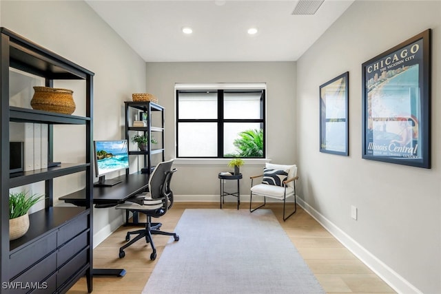 office space with baseboards, visible vents, and wood finished floors