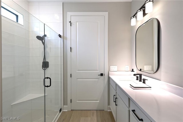 bathroom with a stall shower, vanity, and wood finished floors