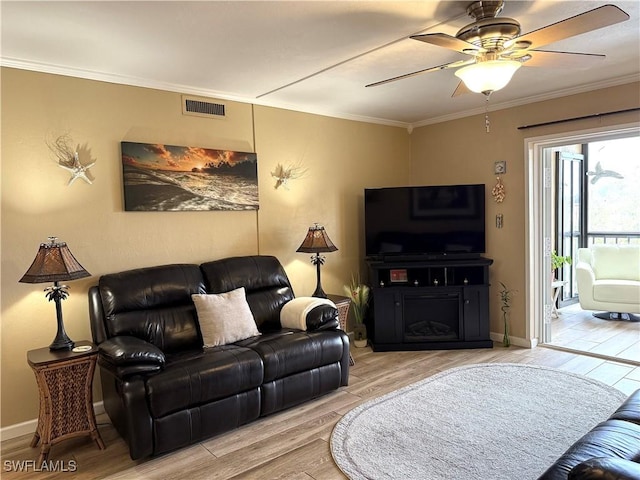 living room with light hardwood / wood-style flooring, ornamental molding, and ceiling fan