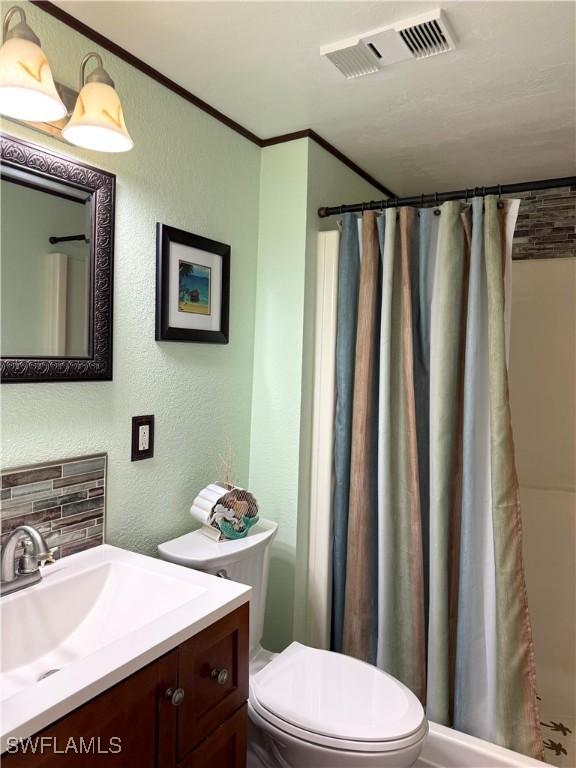 bathroom with toilet, ornamental molding, vanity, a shower with shower curtain, and decorative backsplash