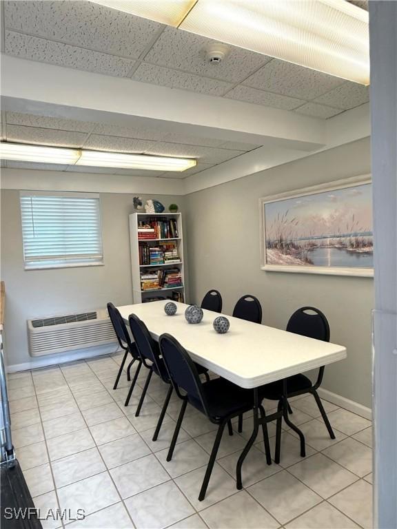 tiled dining area with a paneled ceiling and a wall unit AC