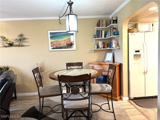 dining room with crown molding and light hardwood / wood-style flooring