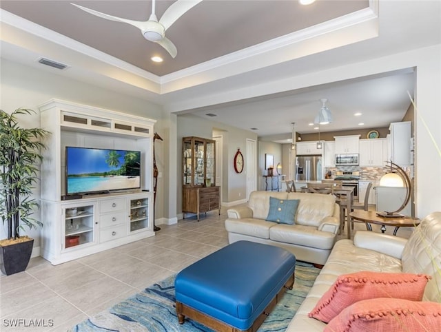 living room with light tile patterned floors, crown molding, a raised ceiling, and ceiling fan