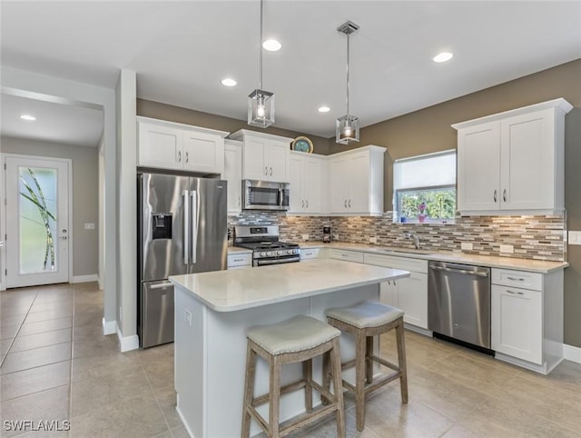 kitchen featuring white cabinetry, appliances with stainless steel finishes, a center island, and decorative light fixtures