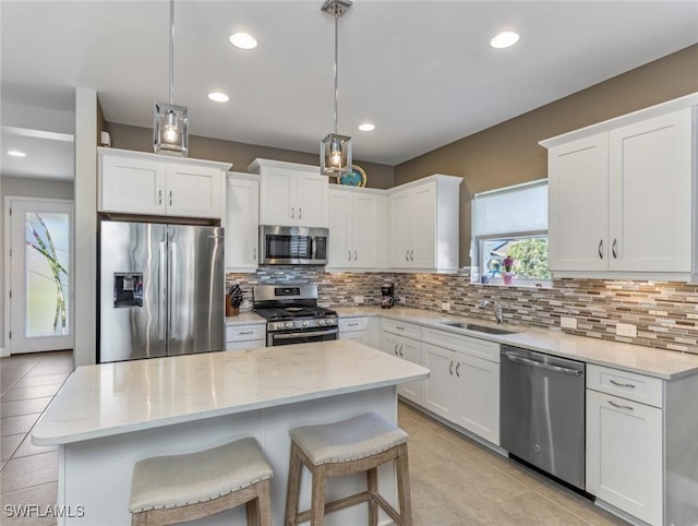 kitchen with hanging light fixtures, white cabinetry, appliances with stainless steel finishes, and sink