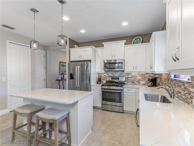 kitchen featuring appliances with stainless steel finishes, decorative light fixtures, a center island, and sink