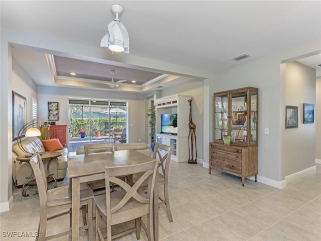 tiled dining space with crown molding, a tray ceiling, and ceiling fan