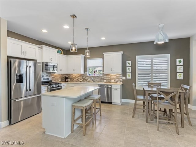 kitchen featuring stainless steel appliances, hanging light fixtures, a kitchen island, and white cabinets