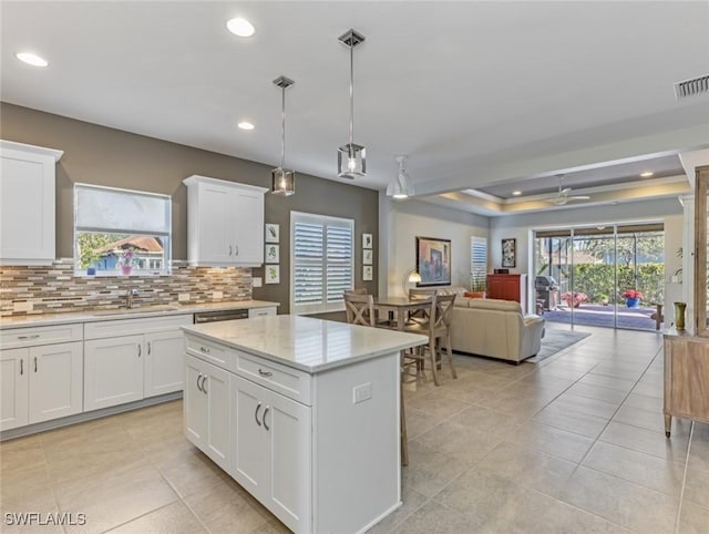 kitchen featuring sink, a center island, white cabinets, pendant lighting, and backsplash