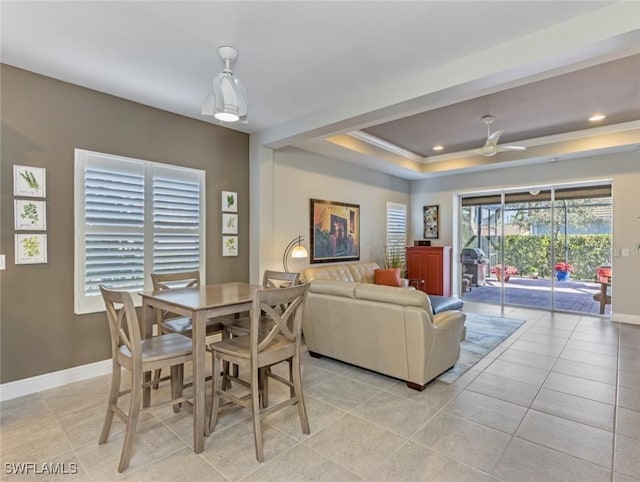 tiled dining room with ornamental molding, ceiling fan, and a tray ceiling