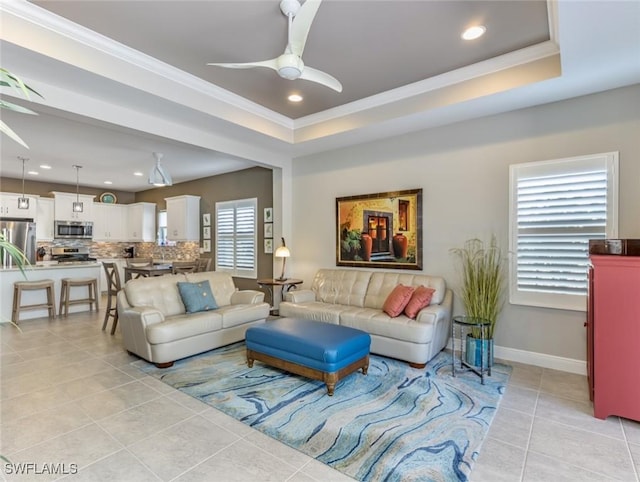 tiled living room featuring crown molding, a raised ceiling, and ceiling fan