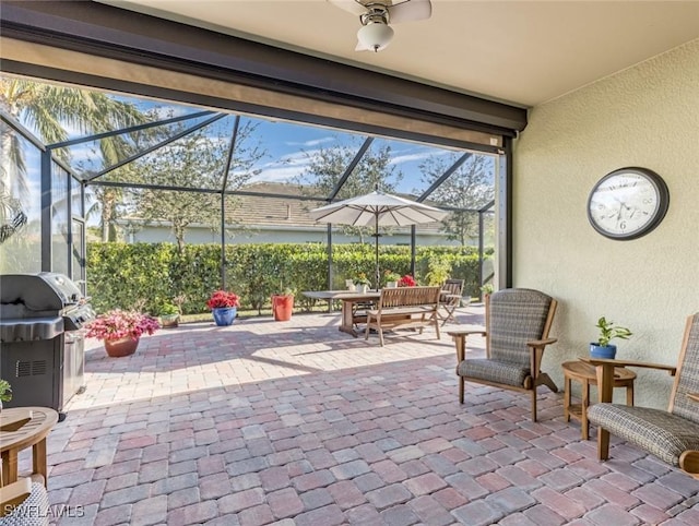 view of patio / terrace with ceiling fan, area for grilling, and glass enclosure