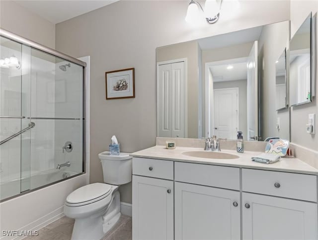 full bathroom with tile patterned flooring, bath / shower combo with glass door, vanity, and toilet