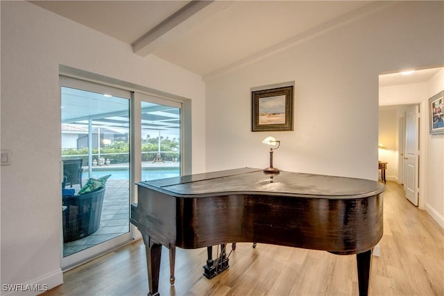 living area featuring vaulted ceiling with beams, light wood finished floors, baseboards, and a sunroom