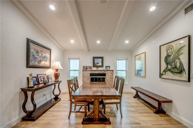 dining space with a wealth of natural light, visible vents, beamed ceiling, and light wood-style flooring