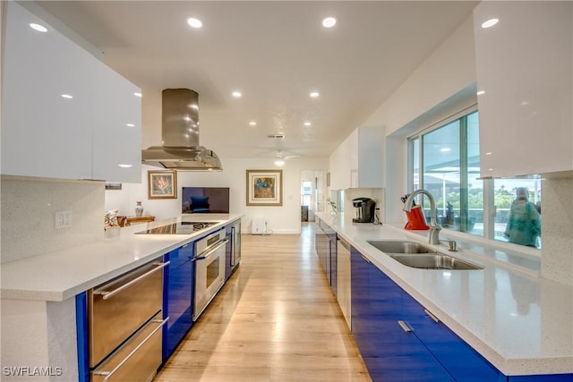 kitchen featuring island exhaust hood, modern cabinets, white cabinetry, and a sink