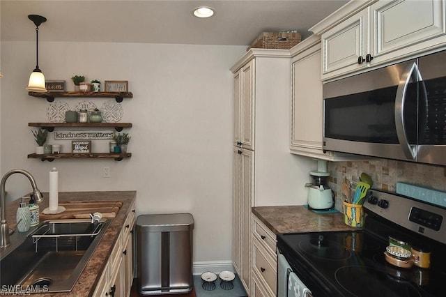 kitchen featuring appliances with stainless steel finishes, pendant lighting, sink, backsplash, and cream cabinets