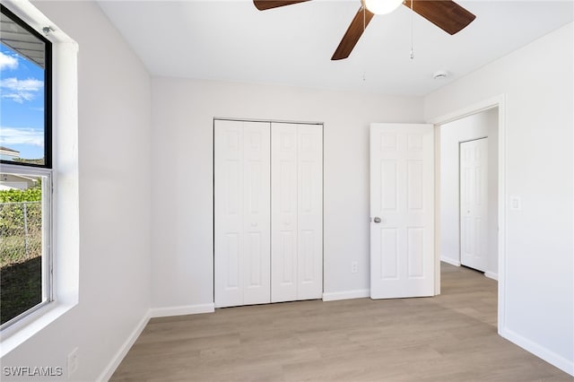 unfurnished bedroom with ceiling fan, light wood-type flooring, and a closet