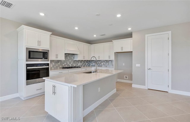 kitchen featuring appliances with stainless steel finishes, sink, a center island with sink, and white cabinets