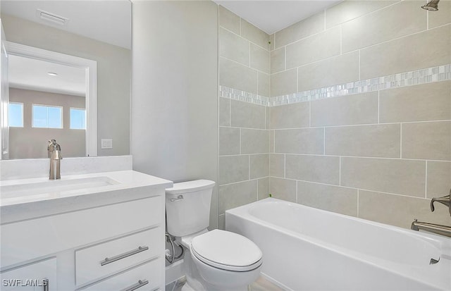 full bathroom with tiled shower / bath, vanity, and toilet