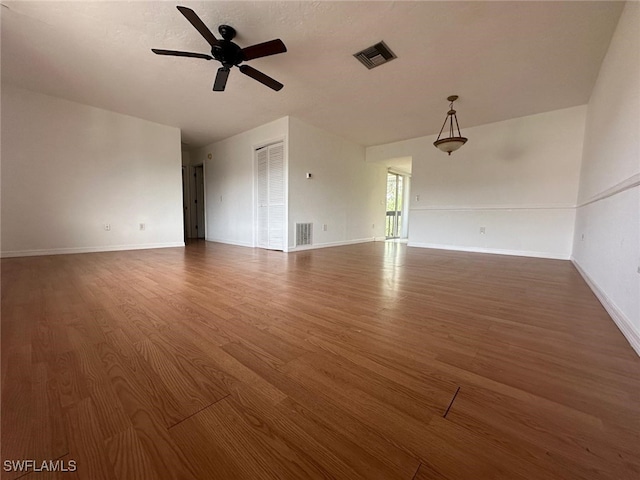 unfurnished living room featuring dark wood-type flooring and ceiling fan