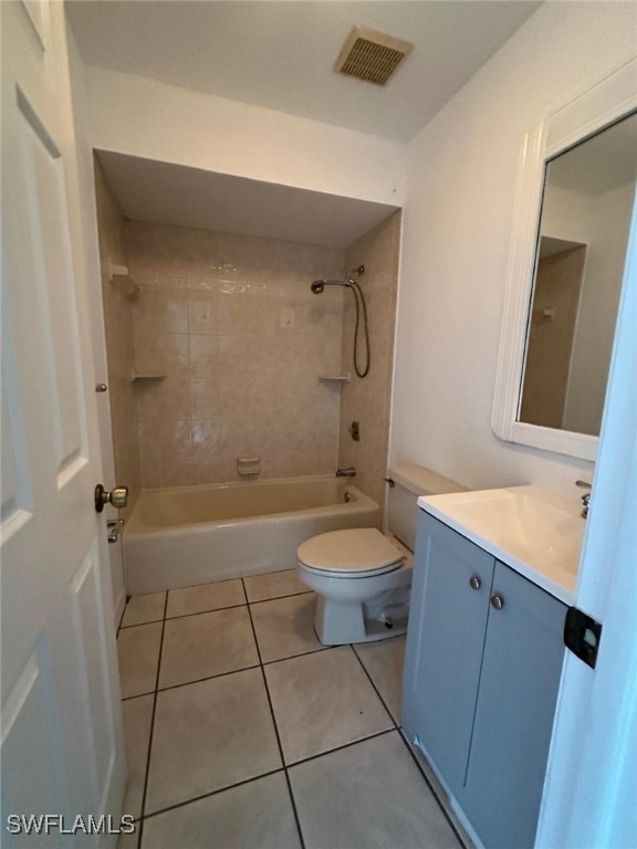 full bathroom featuring vanity, toilet, tiled shower / bath combo, and tile patterned flooring