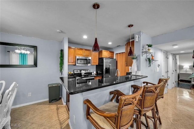 kitchen featuring light tile patterned flooring, decorative light fixtures, a kitchen bar, kitchen peninsula, and stainless steel appliances