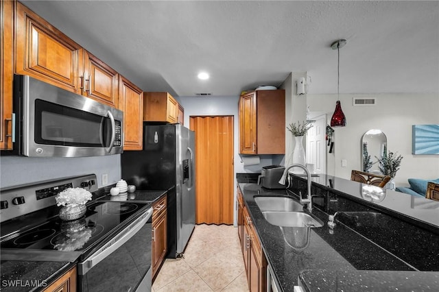 kitchen featuring sink, light tile patterned floors, dark stone countertops, pendant lighting, and stainless steel appliances