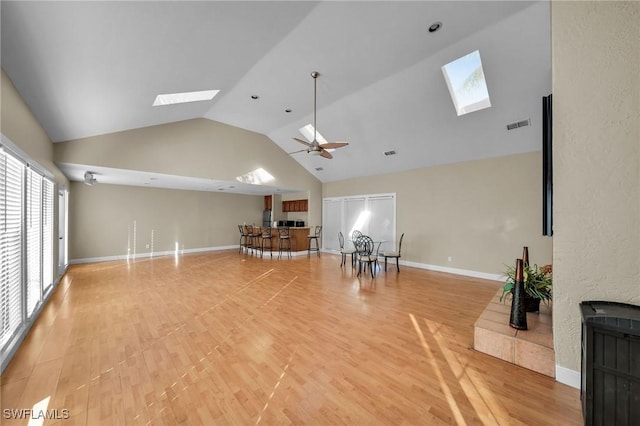 living room featuring wood-type flooring, high vaulted ceiling, ceiling fan, and a skylight