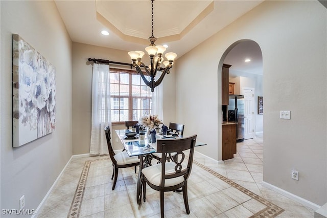 dining area featuring an inviting chandelier and a tray ceiling