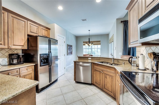 kitchen featuring light stone counters, sink, pendant lighting, and appliances with stainless steel finishes