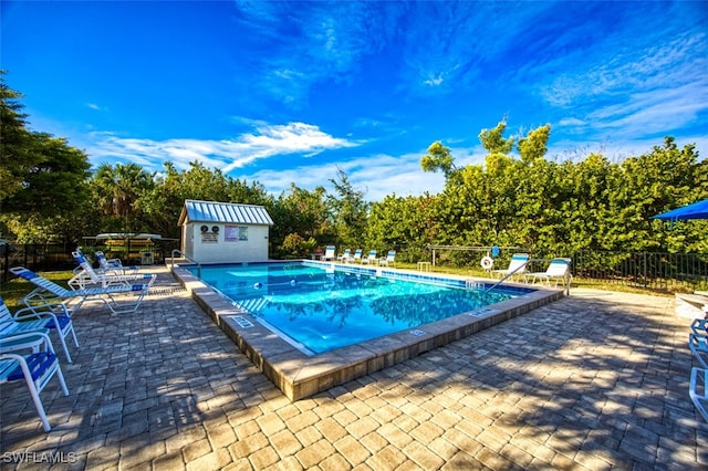 pool featuring a patio area, fence, and an outdoor structure