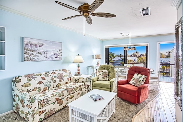 living area featuring visible vents, ornamental molding, wood finished floors, baseboards, and ceiling fan with notable chandelier